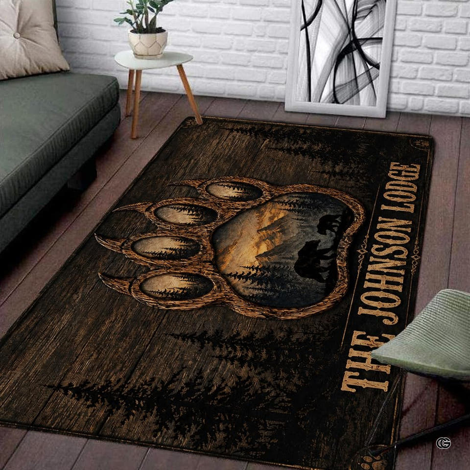 Rustic area rug showing a bear paw print with sunset mountain scene on dark wood planks.