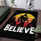 Chillgen area rug displaying a retro Bigfoot silhouette walking past pine trees before a striped sunset.