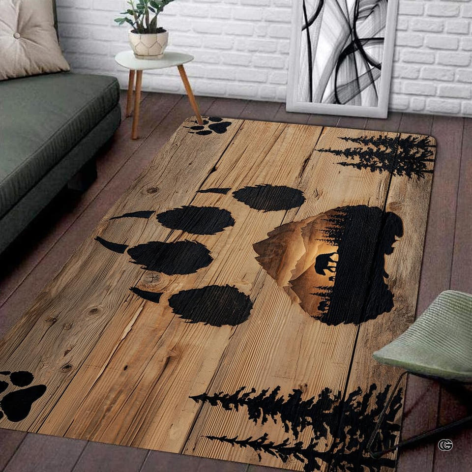 Rustic area rug showing a bear paw print with mountain landscape on wood planks.