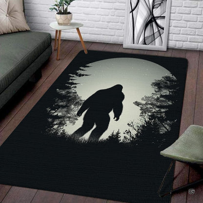 Bigfoot Sasquatch silhouette walking beneath silver full moon in forest rectangular area rug. - thumbnail image 1 of 5