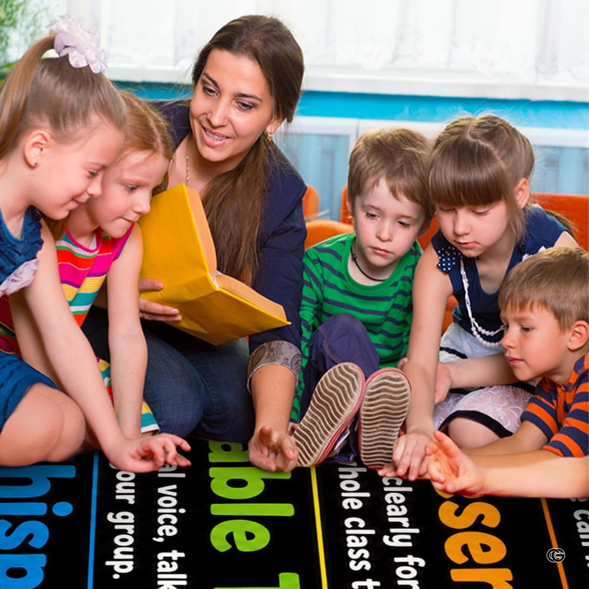 Lifestyle scene featuring teacher and students gathered around educational area rug. - image 5 of 7