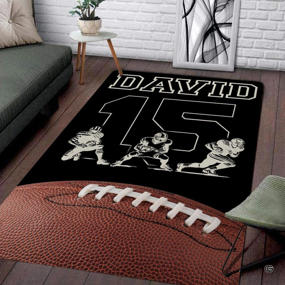 Football players action silhouette rectangular area rug with pebbled ball displayed on wood living room flooring.