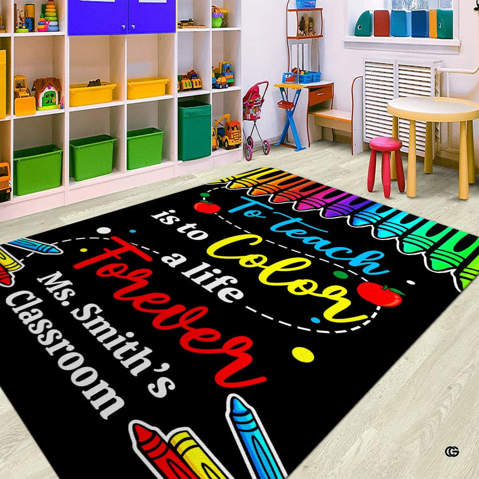 Top-down view of the black chalkboard Classroom Area Rug with rainbow crayons, red apples, and colorful lettering.