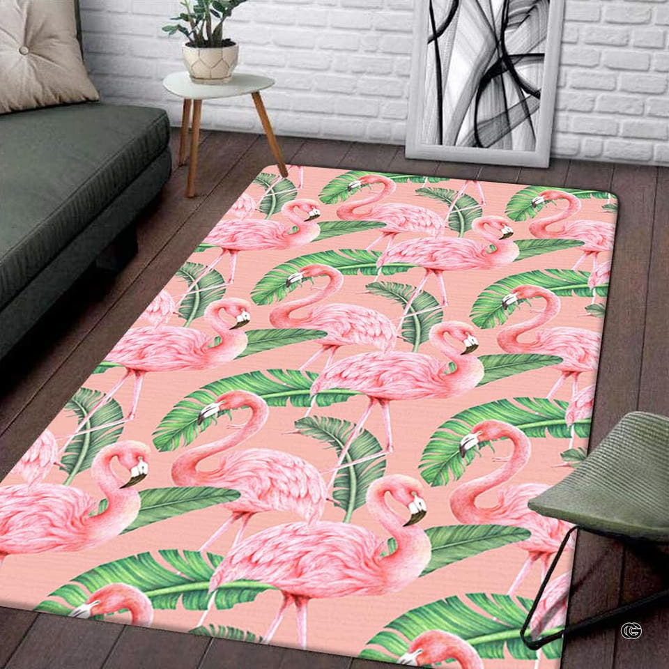 Living room display of a rectangular tropical pink flamingo and palm leaves pattern area rug on wood floor.