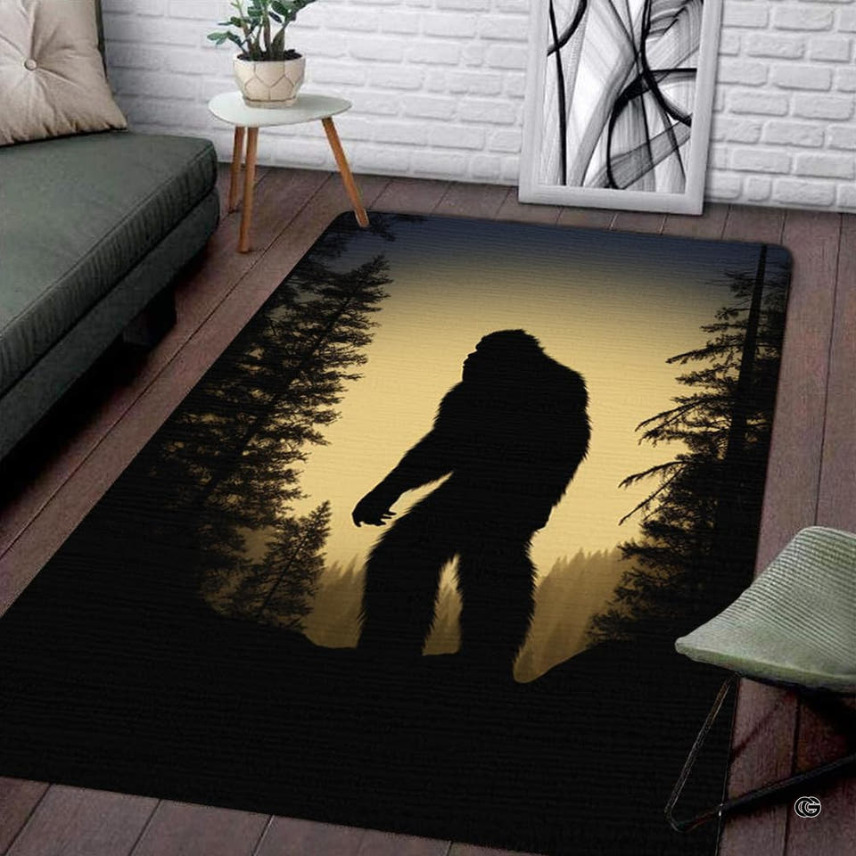 Bigfoot silhouette walking through dense pine tree forest against amber sky area rug display.