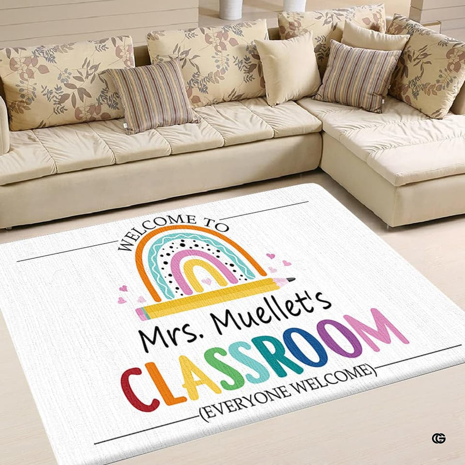 Rectangular white rainbow classroom rug with hand-drawn arches over a yellow wooden pencil and pink hearts.