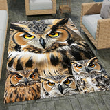 Full overhead view of a bold graphic area rug featuring a horned owl family with amber eyes and ochre plumage.