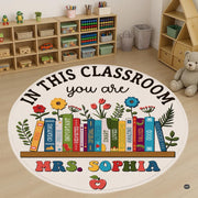 Circular area rug featuring colorful bookshelf spines, sprouting daisies, tulips, and a red apple motif. - thumbnail image 1 of 7