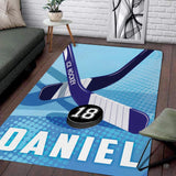 Modern graphic area rug displaying crossed athletic sticks and puck artwork in navy blue and cyan.